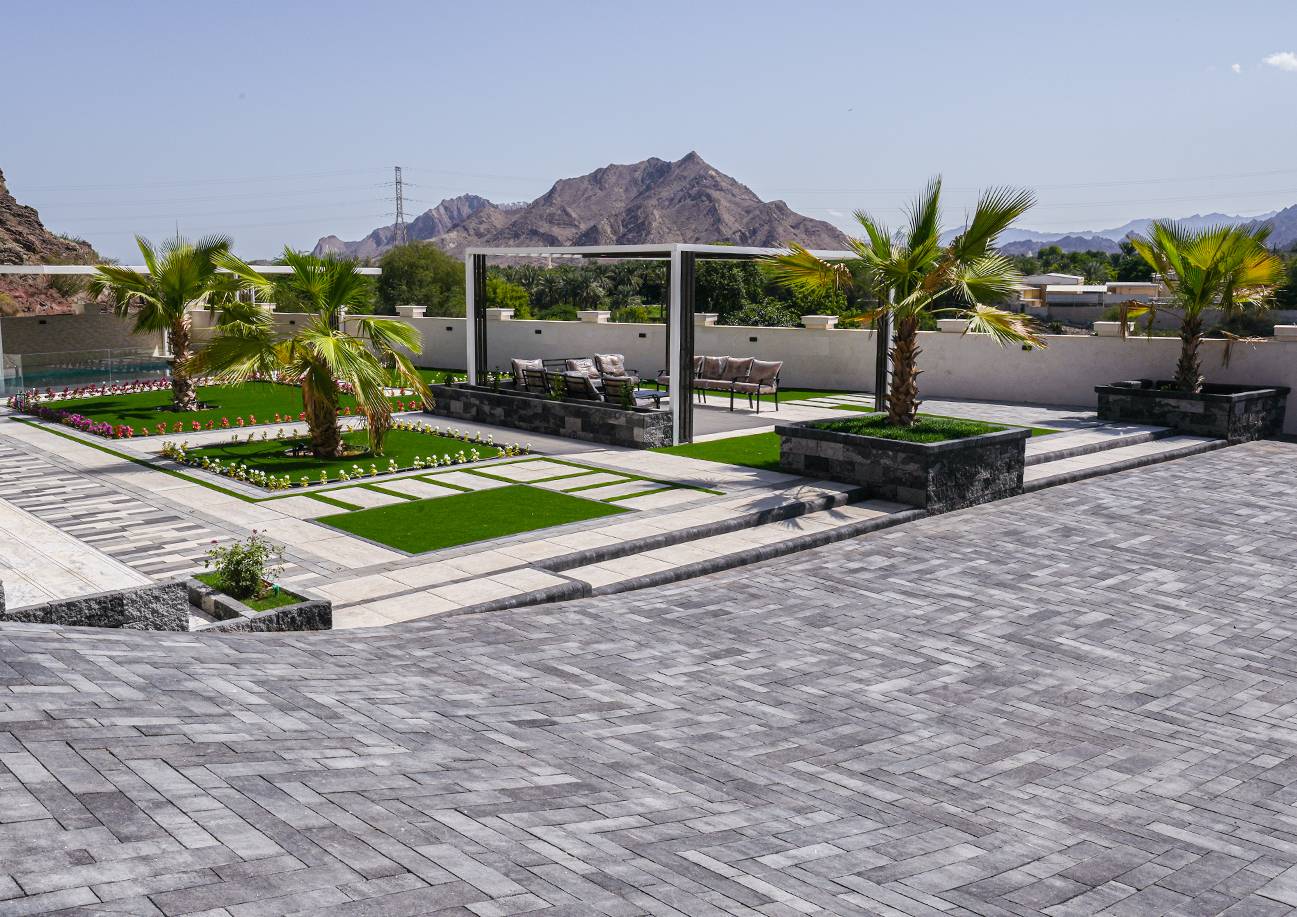 Outdoor villa garden with pavers, lawn, and seating areas
